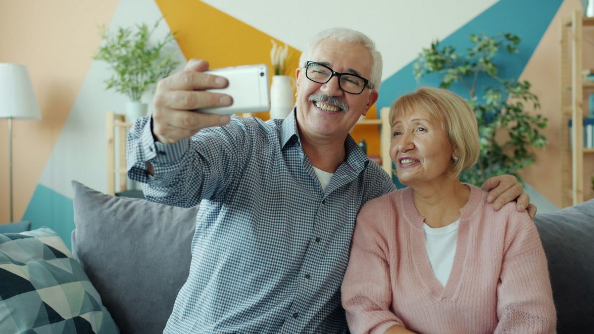 An older couple taking a selfie together on the couch